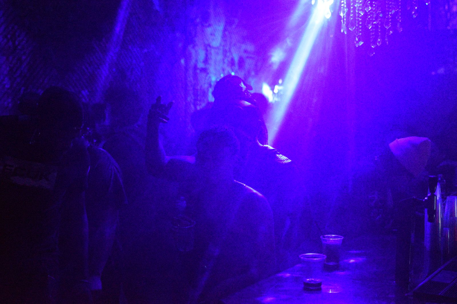 Hands up against purple haze on a crowded floor